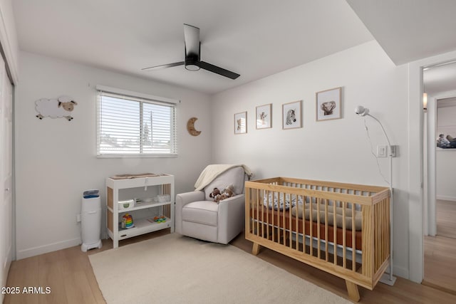 7811 N 32nd Ave, Phoenix, AZ 85051 - bedroom featuring baseboards, a crib, wood finished floors, and a ceiling fan