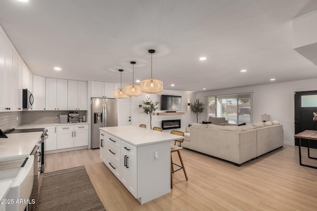 7811 N 32nd Ave, Phoenix, AZ 85051 - kitchen featuring tasteful backsplash, light wood finished floors, appliances with stainless steel finishes, and a kitchen bar