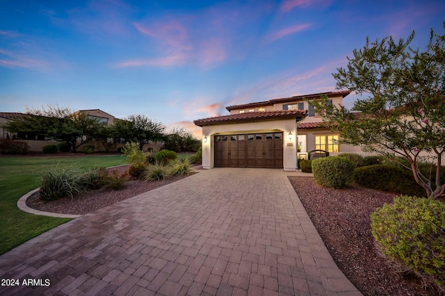 mediterranean / spanish-style home featuring a lawn and a garage