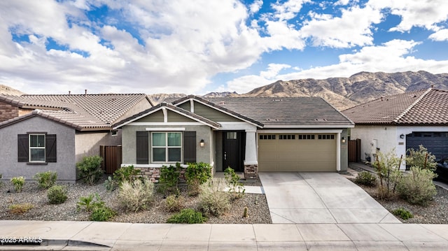 view of front of house featuring concrete driveway, a mountain view, an attached garage, and stone siding