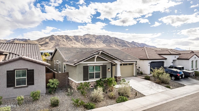 view of front of property featuring an attached garage, fence, stucco siding, driveway, and a mountain view