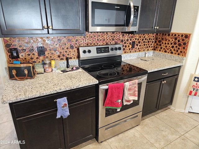 kitchen with decorative backsplash, light stone counters, light tile patterned floors, and appliances with stainless steel finishes