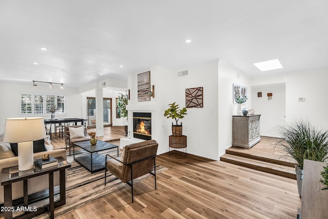 7832 E Via Marina, Scottsdale, AZ 85258 - living area with light wood-style floors, a glass covered fireplace, recessed lighting, and a skylight