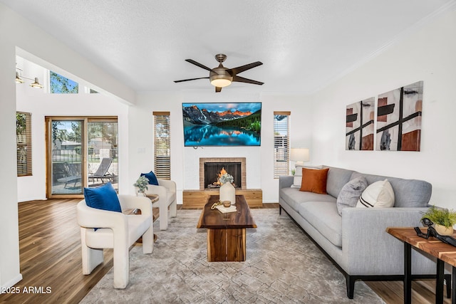 7832 E Via Marina, Scottsdale, AZ 85258 - living area featuring wood finished floors, a ceiling fan, a fireplace, a textured ceiling, and ornamental molding
