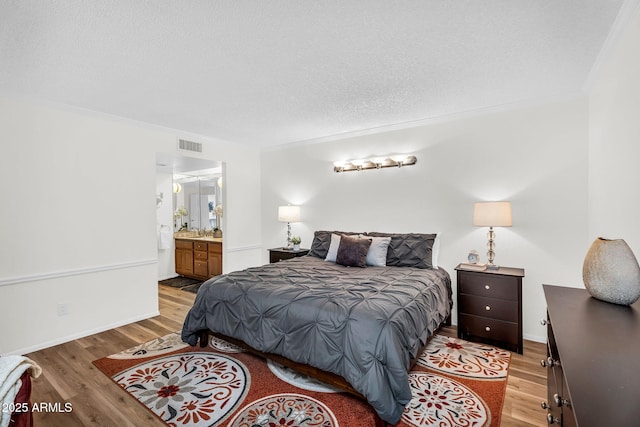 7832 E Via Marina, Scottsdale, AZ 85258 - bedroom featuring crown molding, light wood-style floors, ensuite bath, and a textured ceiling