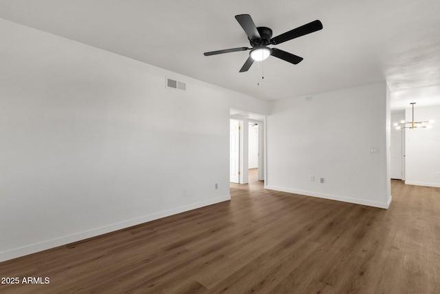 spare room with dark hardwood / wood-style flooring and ceiling fan with notable chandelier