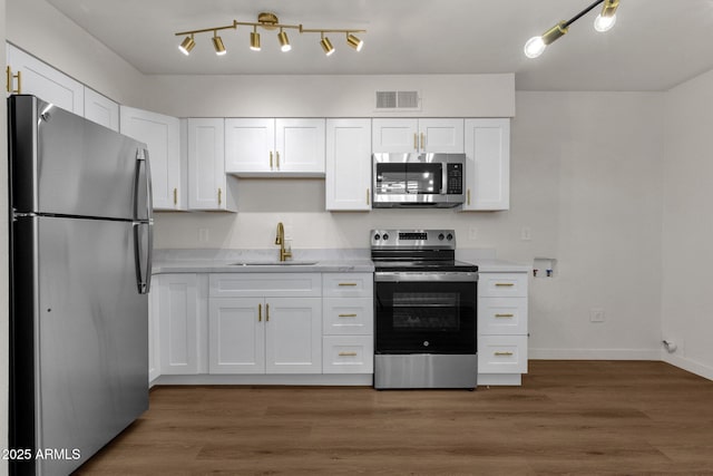 kitchen with dark wood-type flooring, white cabinets, sink, light stone counters, and stainless steel appliances