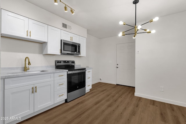 kitchen with stainless steel appliances, white cabinetry, hanging light fixtures, and sink