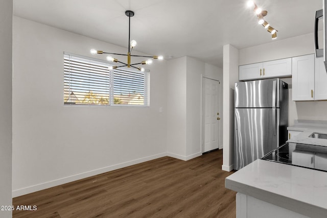 kitchen featuring hanging light fixtures, an inviting chandelier, dark hardwood / wood-style floors, stainless steel fridge, and white cabinets