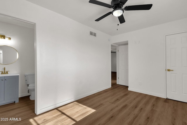 unfurnished bedroom with hardwood / wood-style flooring, ceiling fan, sink, and connected bathroom