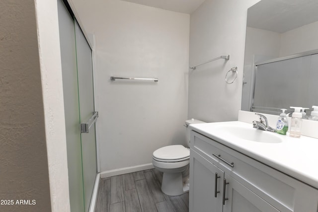 bathroom featuring a stall shower, baseboards, toilet, wood finished floors, and vanity