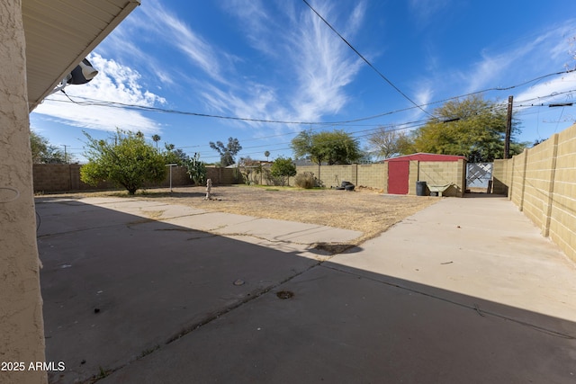 view of patio featuring an outdoor structure, a fenced backyard, and a gate