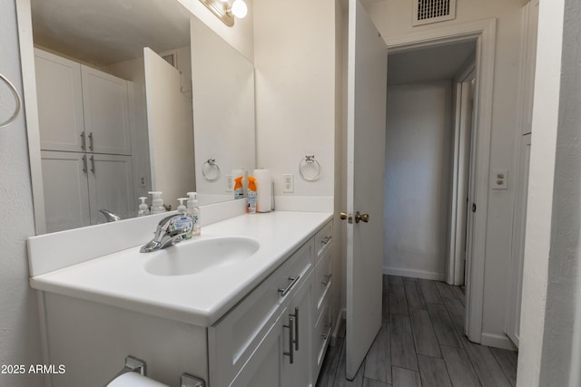 bathroom featuring wood finish floors, visible vents, vanity, and baseboards