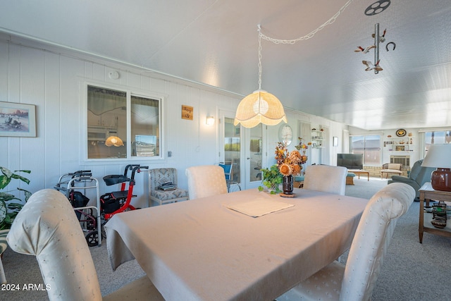 dining space featuring wood walls and carpet flooring