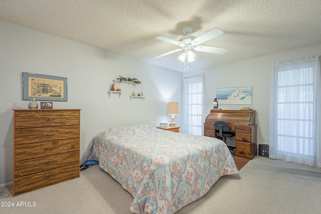 carpeted bedroom with ceiling fan and a textured ceiling