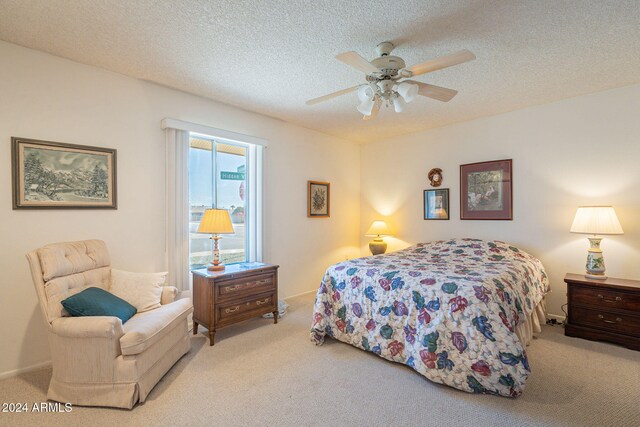 bedroom featuring light carpet, a textured ceiling, and ceiling fan