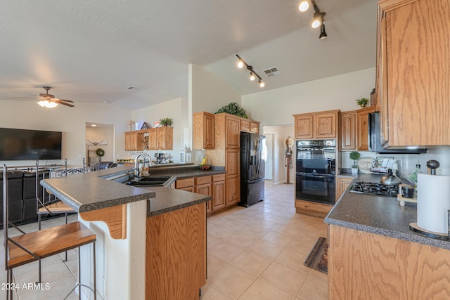 kitchen with sink, kitchen peninsula, lofted ceiling, a breakfast bar area, and black appliances