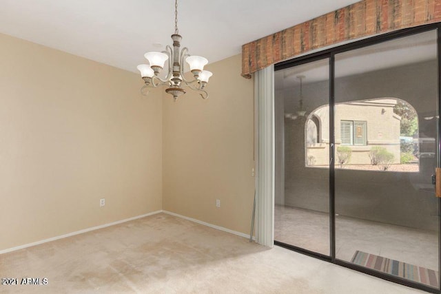 carpeted spare room featuring an inviting chandelier and baseboards