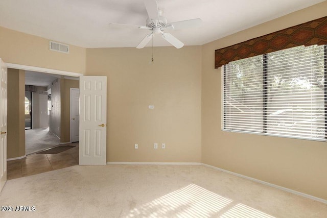 tiled spare room featuring a ceiling fan, carpet, visible vents, and baseboards