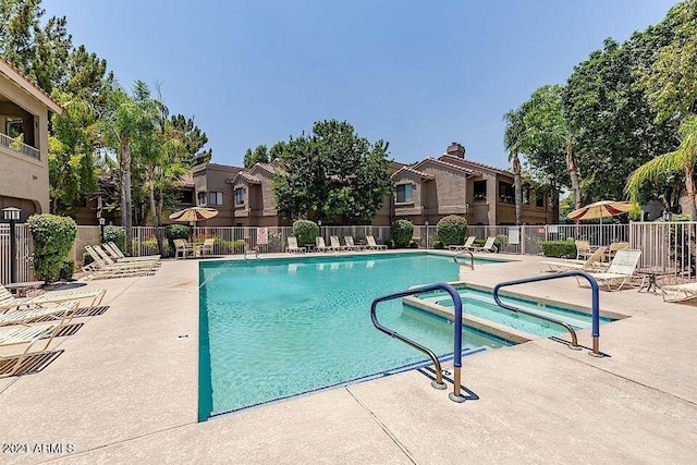 pool with a patio area, fence, a residential view, and a hot tub