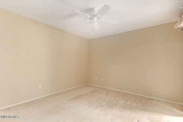 spare room with light colored carpet, baseboards, and ceiling fan