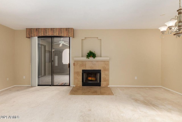 unfurnished living room with an inviting chandelier, carpet flooring, a fireplace, and baseboards