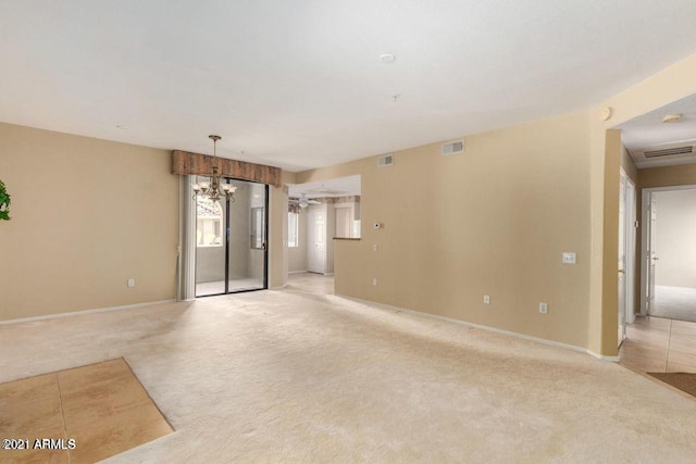 spare room with a chandelier, visible vents, and light carpet