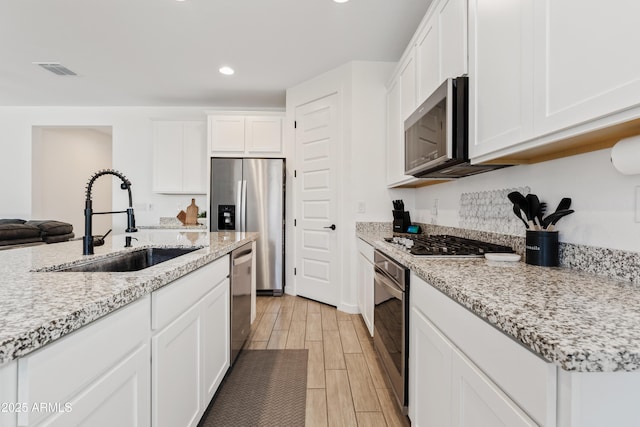 23037 E Domingo Rd, Queen Creek, AZ 85142 - kitchen featuring a sink, appliances with stainless steel finishes, light wood-style floors, white cabinetry, and recessed lighting