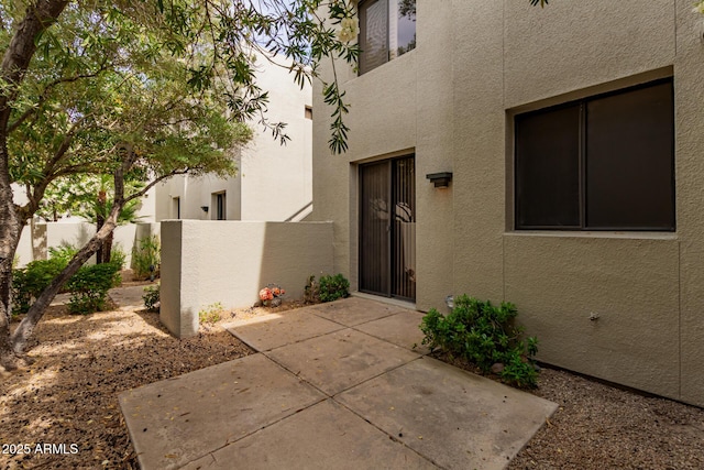 doorway to property featuring fence, a patio area, and stucco siding