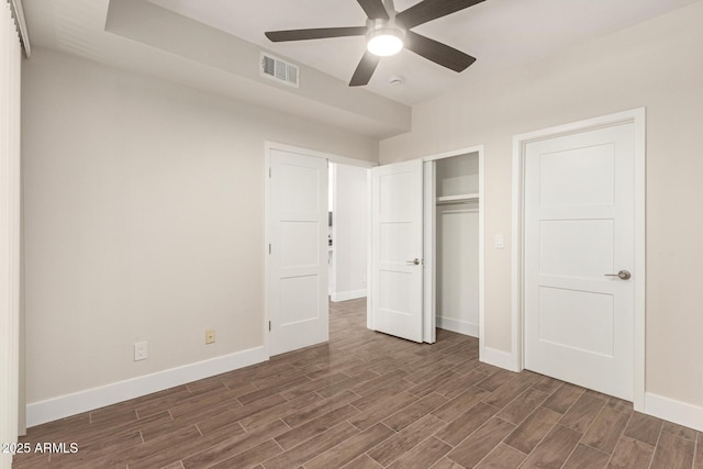 unfurnished bedroom with baseboards, visible vents, wood finished floors, and a closet