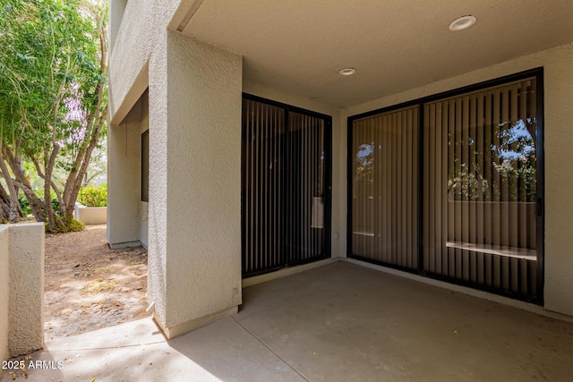 entrance to property with stucco siding and a patio area