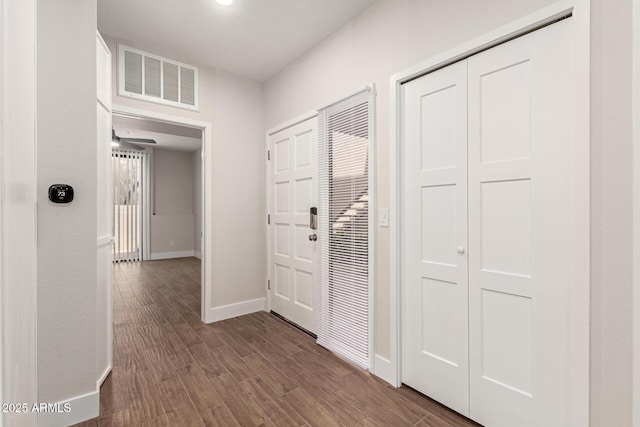 corridor featuring dark wood-style flooring, baseboards, and visible vents