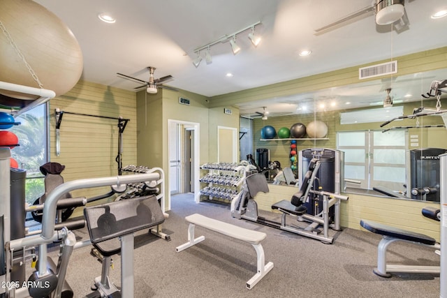 exercise room with visible vents, recessed lighting, ceiling fan, and wood walls