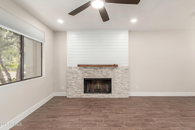 unfurnished living room with baseboards, a fireplace, a ceiling fan, and wood finished floors