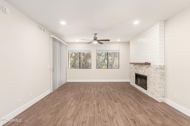 unfurnished living room featuring visible vents, wood finished floors, a stone fireplace, ceiling fan, and recessed lighting
