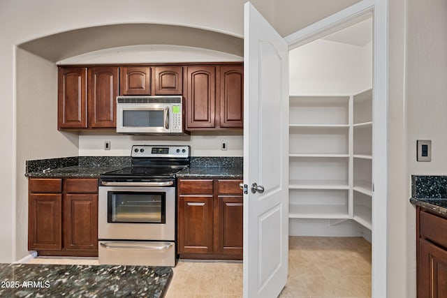 kitchen with dark stone countertops, light tile patterned floors, and appliances with stainless steel finishes