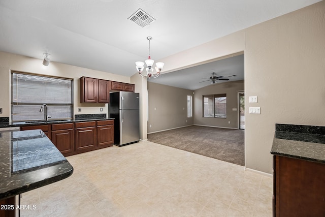 kitchen with sink, stainless steel fridge, light carpet, decorative light fixtures, and vaulted ceiling