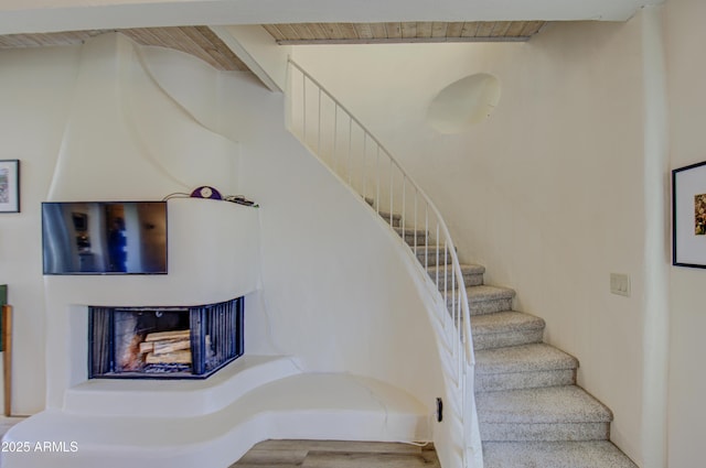 stairway with a fireplace and wood ceiling