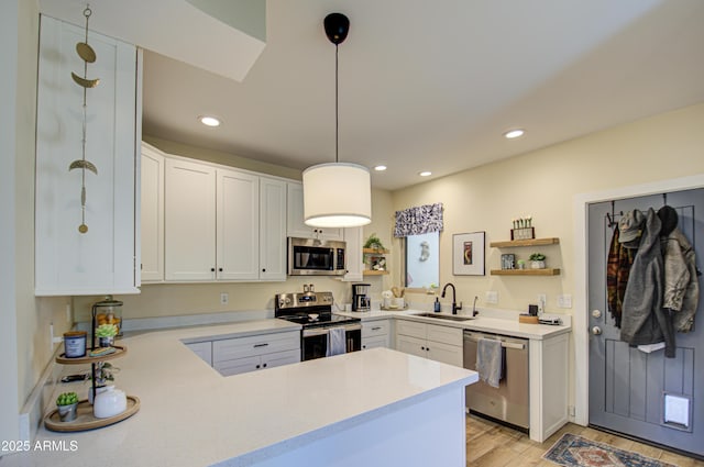 kitchen featuring white cabinetry, kitchen peninsula, hanging light fixtures, and stainless steel appliances