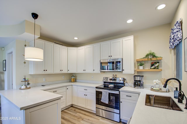 kitchen with white cabinetry, kitchen peninsula, stainless steel appliances, hanging light fixtures, and sink