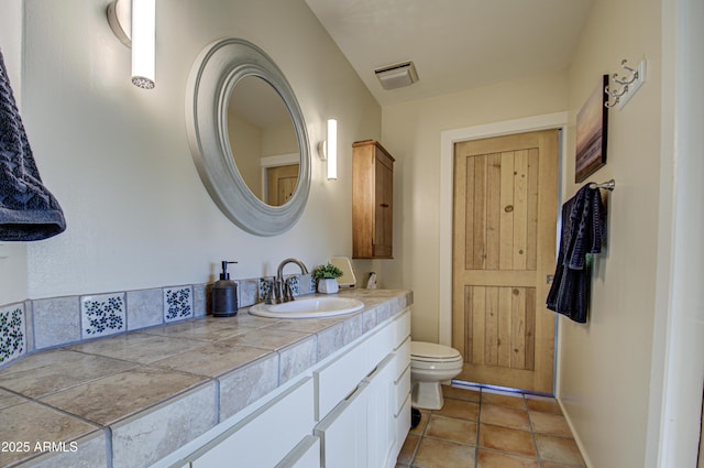 bathroom with toilet, vanity, and tile patterned floors