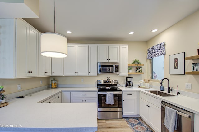 kitchen featuring light hardwood / wood-style floors, pendant lighting, sink, stainless steel appliances, and white cabinets