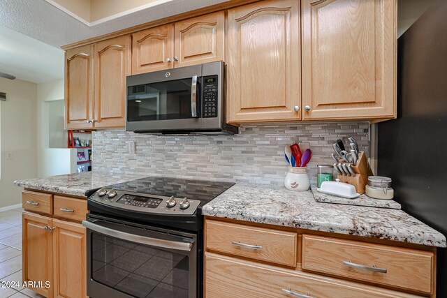 kitchen featuring light stone countertops, appliances with stainless steel finishes, and tasteful backsplash