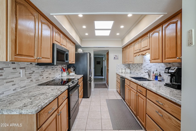 kitchen featuring a raised ceiling, sink, backsplash, appliances with stainless steel finishes, and light stone countertops