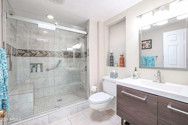 bathroom with tile patterned floors, a shower with door, vanity, and toilet