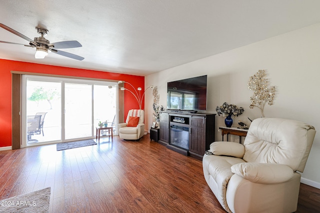 living room with a fireplace, dark hardwood / wood-style flooring, and ceiling fan