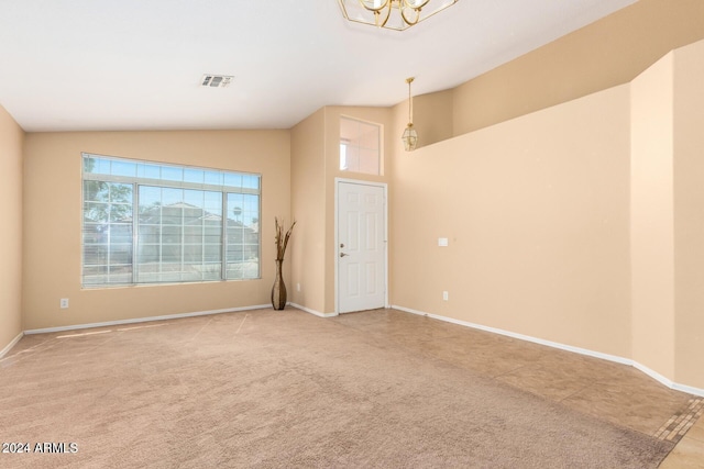 carpeted spare room with lofted ceiling and a notable chandelier