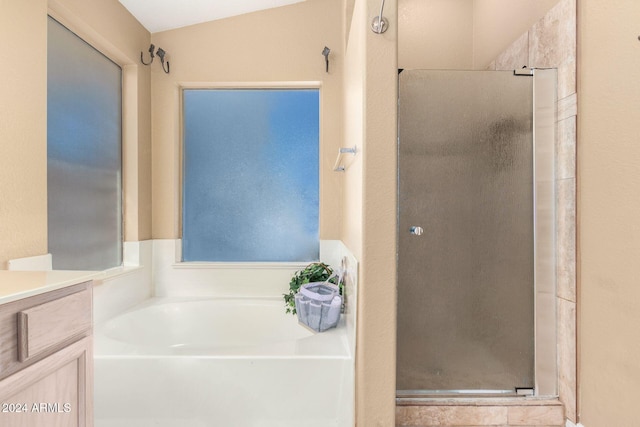 bathroom featuring vanity, vaulted ceiling, and shower with separate bathtub