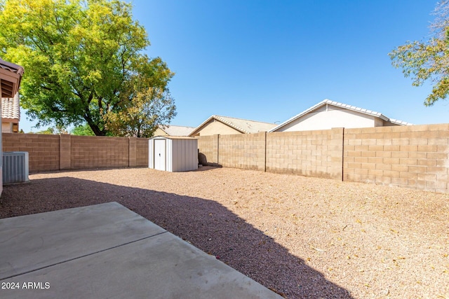 view of yard featuring central AC, a patio, and a shed