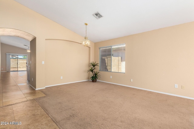 empty room featuring ceiling fan with notable chandelier, carpet, and vaulted ceiling